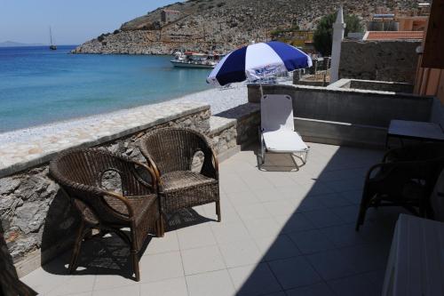 a patio with chairs and an umbrella next to the water at Villa Zeus in Symi