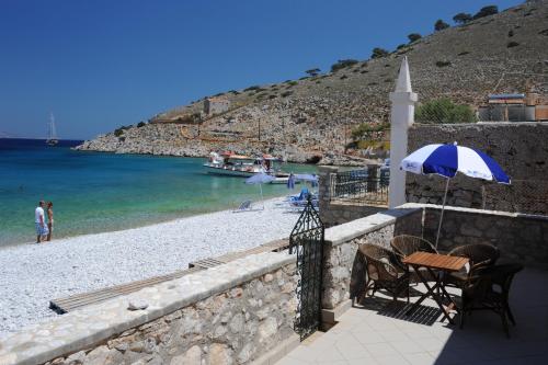 a table and chairs with an umbrella on a beach at Villa Zeus in Symi
