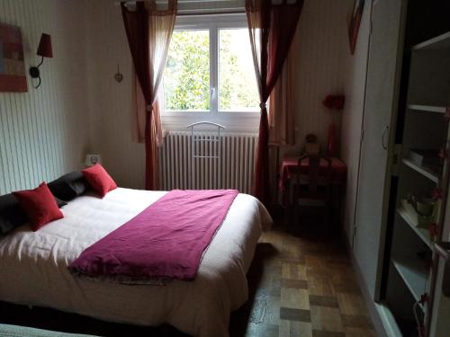 a bedroom with a bed with red pillows and a window at Havre de paix au bords de l'Eure - divers hébergements in Neuilly