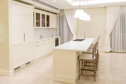a kitchen with white cabinets and a white island with chairs at SUITE WA B2 - WALDORF ASTORIA RESIDENCES - JERUSALEM-RENT in Jerusalem