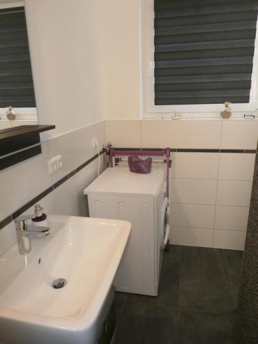 a white bathroom with a sink and a radiator at Ferienwohnung am Seglerhafen in Peenemünde