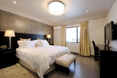 a bedroom with a large white bed and a window at Villa Moyal in Johannesburg