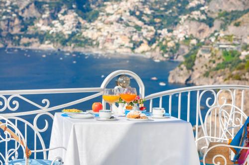 a table with food and drinks on a balcony with the ocean at Hotel Smeraldo in Praiano