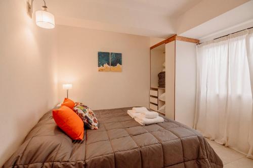 1 dormitorio con 1 cama con almohadas de color naranja en Appartement in the Main Street with elevator access en Ushuaia