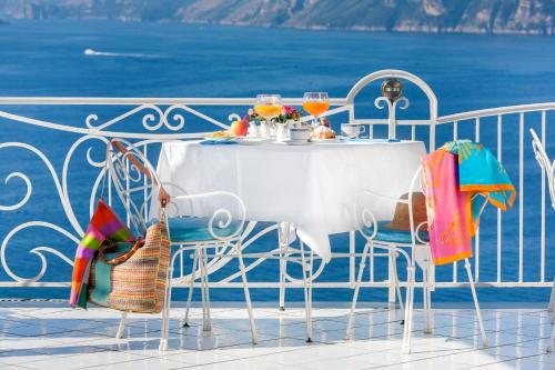 a white table and chairs on a balcony with the ocean at Hotel Smeraldo in Praiano