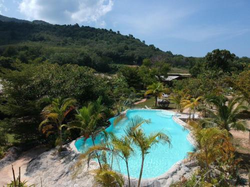 una piscina con palmeras y una montaña en Koh Pu Villa, en Ko Jum