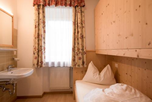una camera con letto, lavandino e finestra di Residence Sisi a Ortisei