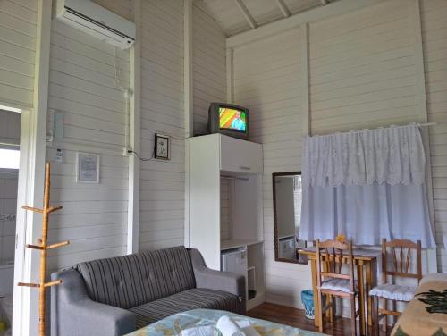 sala de estar con sofá y TV en la pared en Pousada Landhaus, en Urubici