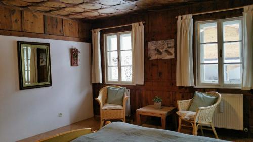 a bedroom with two chairs and a bed and windows at Villa Zeppelin - App Bergkristall in Bramberg am Wildkogel