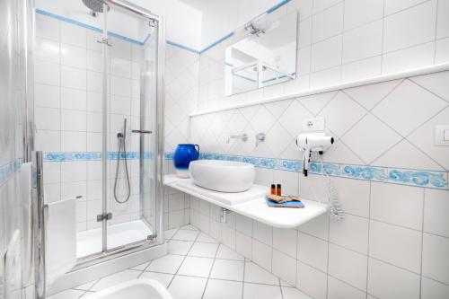 a white bathroom with a sink and a shower at Hotel Smeraldo in Praiano