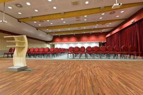 an empty auditorium with red chairs and a podium at Hotel Poznański A2 in Poznań