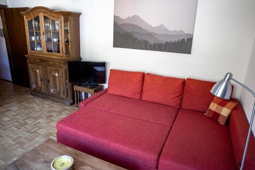 a red couch in a living room with a television at Apartment Hava in Bad Hofgastein