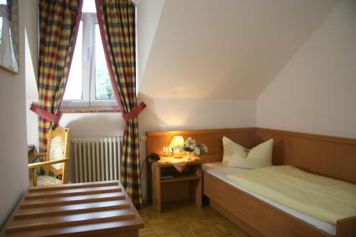 a small bedroom with a bed and a table at Hotel-Gasthof Eberherr in Forstinning