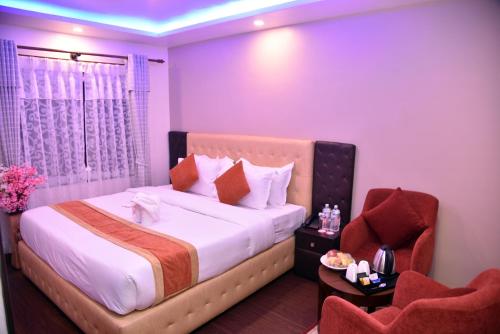 Habitación de hotel con cama y silla en Marinha Airport Hotel, en Katmandú