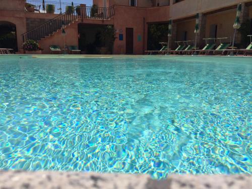 a pool of blue water with chairs in a building at Hotel Villa Gemella in Baja Sardinia