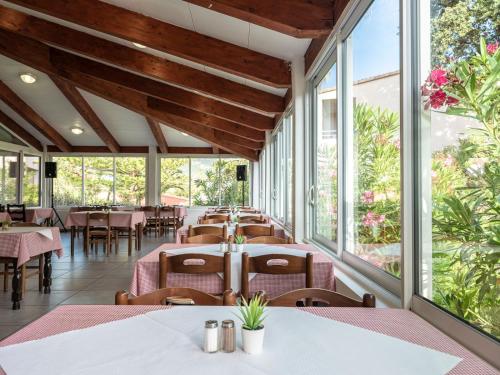 a restaurant with tables and chairs and windows at Ferienhotel Maristella in Algajola