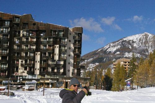 a man taking a picture of a building in the snow at Studio Le Boussolenc in Les Orres