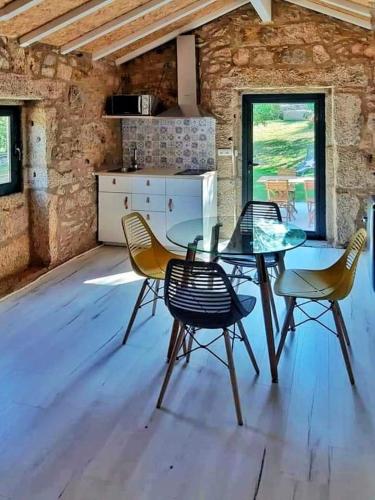a dining room with a glass table and chairs at River House Sejães in Oliveira de Frades