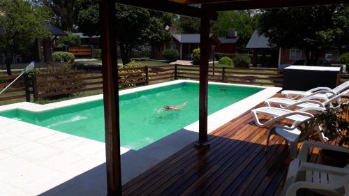 a person swimming in a swimming pool on a wooden deck at Der Wald cabañas in Los Reartes