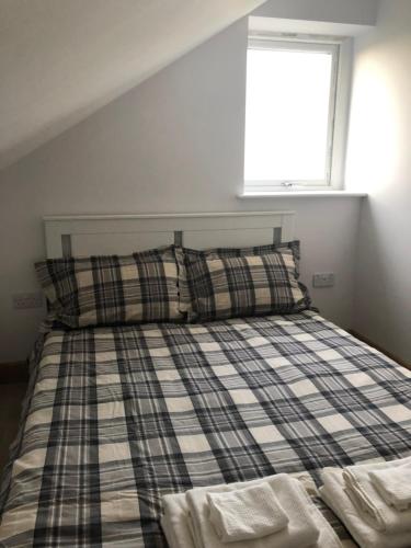 a bedroom with a bed with plaid pillows and a window at quiet secluded loft in County Durham in Durham