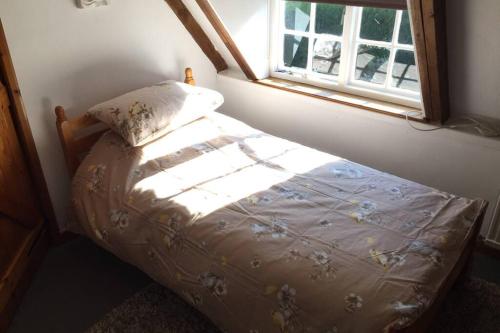 een klein bed in een kamer met een raam bij Rose Cottage in Ludham