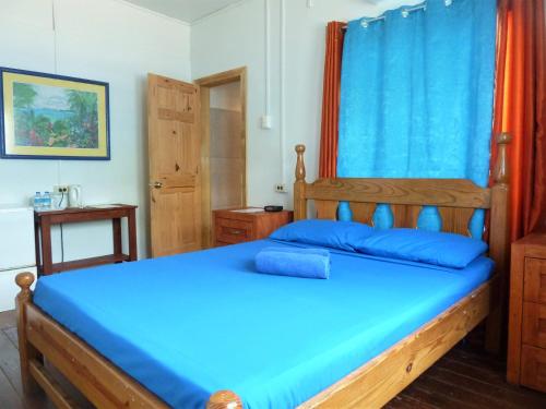 a bedroom with a wooden bed with blue sheets at Miller's Guest House in Buccoo