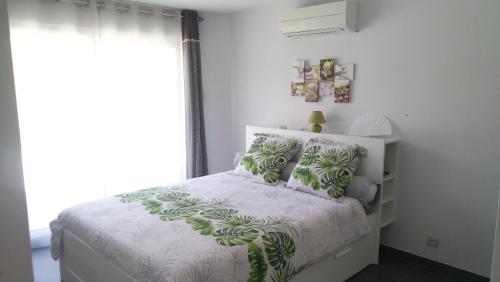 a white bedroom with a bed with green pillows at Villa Dikaria in Montacher