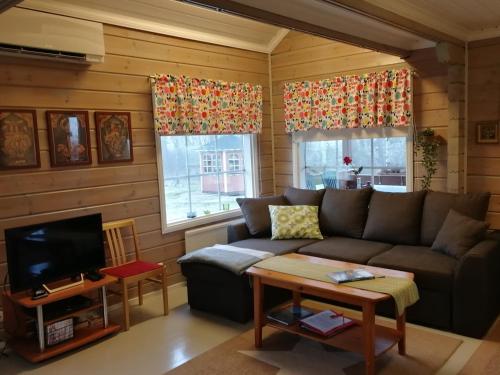 a living room with a couch and a tv at Silfvastas Holiday Homes in Lapinjärvi