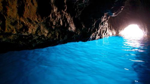 a dark cave with blue water in it at Luna Caprese Guest House in Anacapri