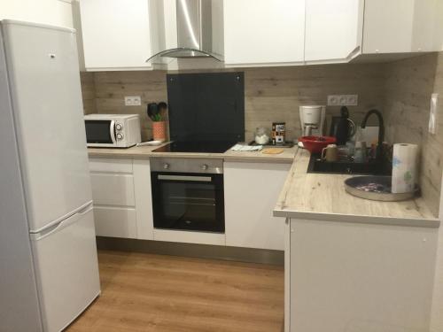 une cuisine avec des armoires blanches et un réfrigérateur blanc dans l'établissement 3 chambres en lit double, 6 personnes, dans appartement entièrement rénové, 70 m2 , WIFI,Climatisation, très calme , tout équipé,lit bébé, à Clermont-Ferrand