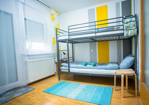 - une chambre avec des lits superposés, une table et un tabouret dans l'établissement Goldenfields apartment, à Kranj