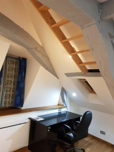 an attic office with a black desk and a chair at Le Nid Douillet in Auxerre