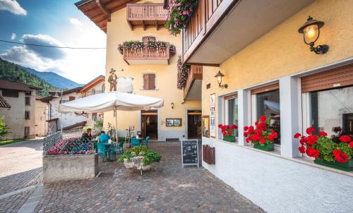 an outdoor cafe with an umbrella and flowers on a building at Albergo Alla Costa in Ledro