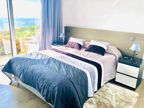 a bedroom with a large bed with a large window at Villa Pinheira II in Estreito da Calheta