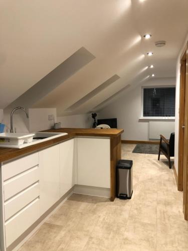 an attic kitchen with white cabinets and a sink at quiet secluded loft in County Durham in Durham