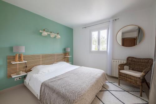 1 dormitorio con cama, silla y espejo en Le Cigalou, en Mallemort