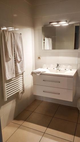 une salle de bain blanche avec un lavabo et un miroir dans l'établissement Hôtel Restaurant Le Relais de l'Estuaire, à Étauliers