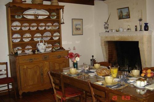 Un comedor con mesa y chimenea. en Chambres d'Hôtes Domaine Le Fragnaud, en Saint-Porchaire