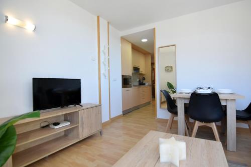 a living room with a television and a dining table at Lux Isard "Acceso directo a pistas" in Pas de la Casa
