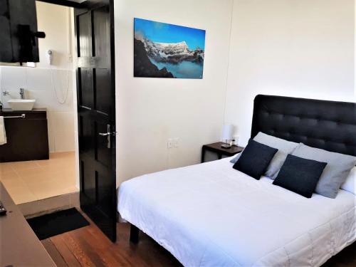 a bedroom with a white bed with a black headboard at El Museo Hotel Boutique in La Paz