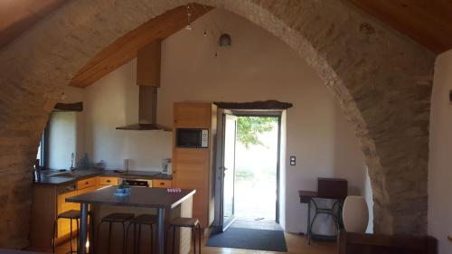 a kitchen with an archway and a table in a room at Le Paillé in Mascourbe