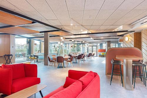 a lobby with red furniture and tables and chairs at Ibis Styles Madrid City Las Ventas in Madrid