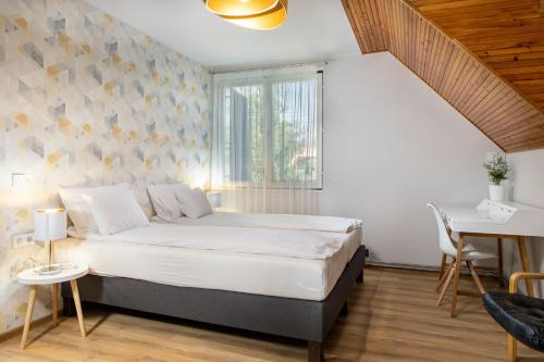 a bedroom with a bed and a table and a window at Tiszapart-Vendégház in Tiszakécske