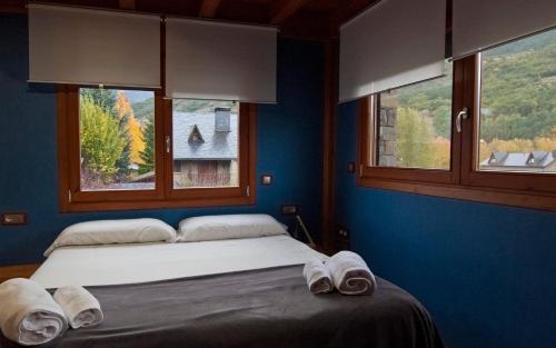 a bedroom with a bed and two windows with towels at Can Congost in Sort