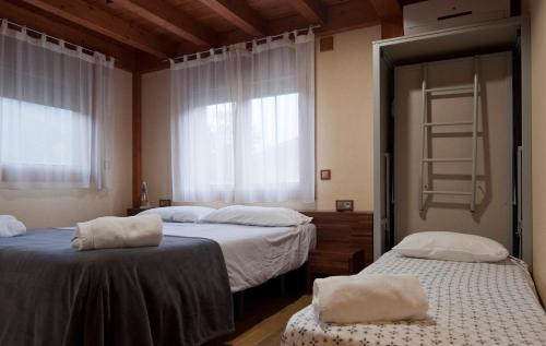 two beds in a room with windows and a ladder at Can Congost in Sort