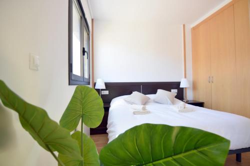 a bedroom with a bed with white sheets and a plant at Lux Aigle "Acceso directo a pistas" in Pas de la Casa