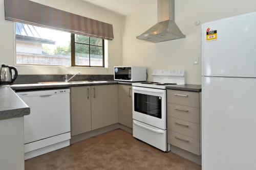 een keuken met witte apparatuur en een witte koelkast bij Metropolitan Motel on Riccarton in Christchurch