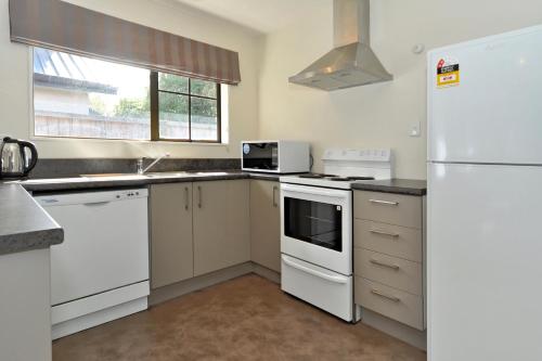 a kitchen with white appliances and a white refrigerator at Metropolitan Motel on Riccarton - 2 mins walk to Westfield in Christchurch