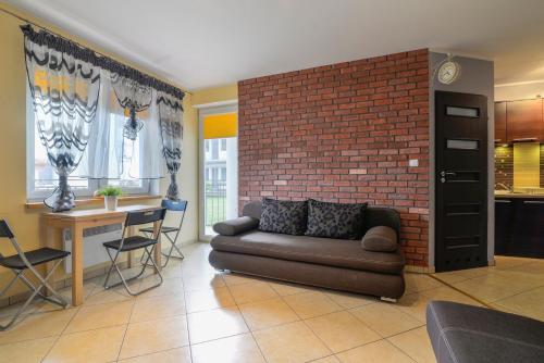 a living room with a couch and a brick wall at APARTAMENT KLAUDIA in Krynica Morska