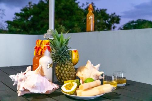 a table topped with a plate of pineapple and fruit at joli appartement avec vue au Moule in Le Moule